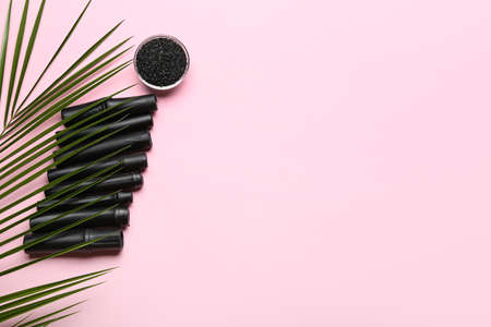Bowl of activated carbon powder, black bamboo sticks and palm leaf on color backgroundの写真素材