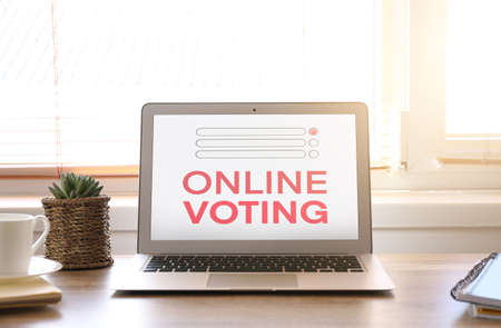 Laptop with text ONLINE VOTING on screen at workplaceの写真素材