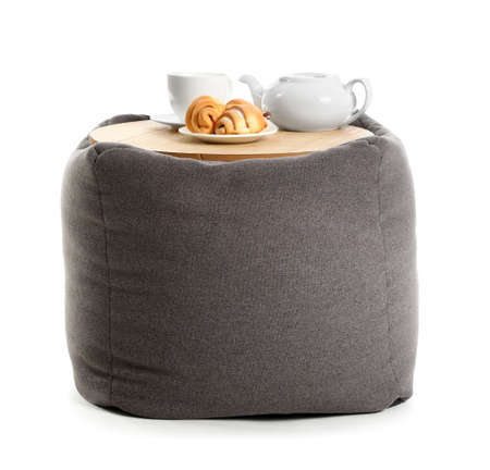 Teapot, cup and bakery on modern pouf on white backgroundの写真素材