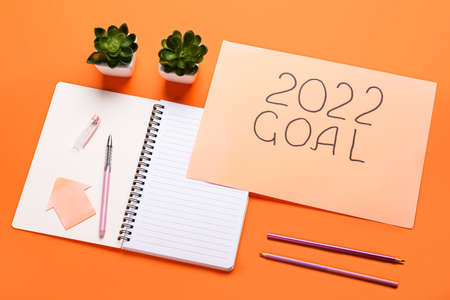 Paper sheet with text 2022 GOAL and stationery on color background