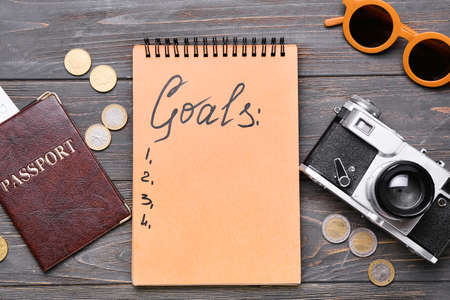 Notebook with empty to do list, passport, coins and photo camera on wooden background. new year...