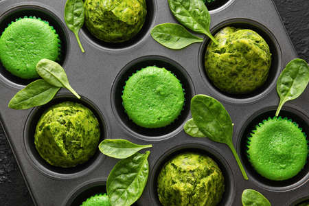 Baking tin with tasty spinach muffins on dark background, closeupの写真素材