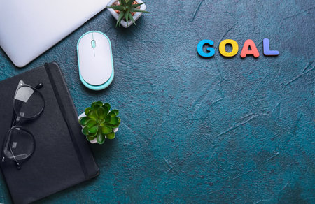 Word GOAL with laptop and notebook on dark background