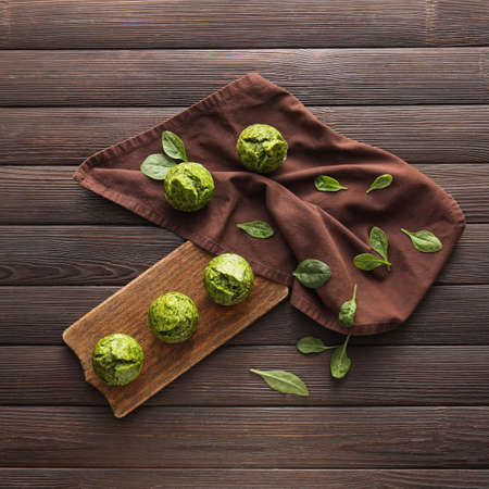 Board with tasty spinach muffins on dark wooden backgroundの写真素材