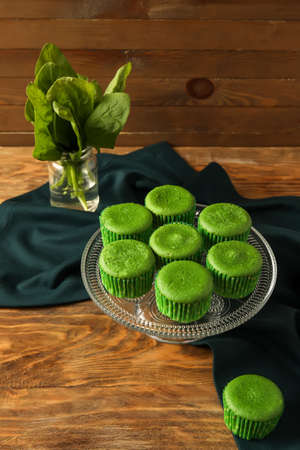 Stand with tasty spinach muffins on wooden backgroundの写真素材