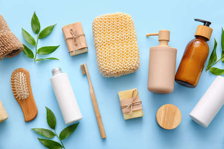 Set of bath supplies with loofah sponge and plant branches on blue background