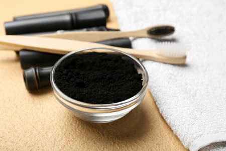 Bowl with activated charcoal tooth powder on beige backgroundの写真素材