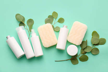 Set of bath supplies with sponges and plant branches on green backgroundの写真素材