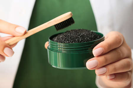 Woman holding jar with activated charcoal tooth powder and brush, closeupの写真素材