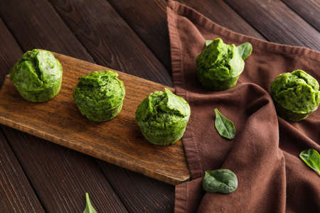 Board with tasty spinach muffins on dark wooden backgroundの写真素材