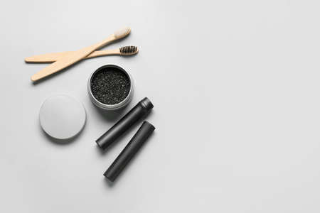 Jar with activated charcoal tooth powder, bamboo sticks and brushes on light backgroundの写真素材