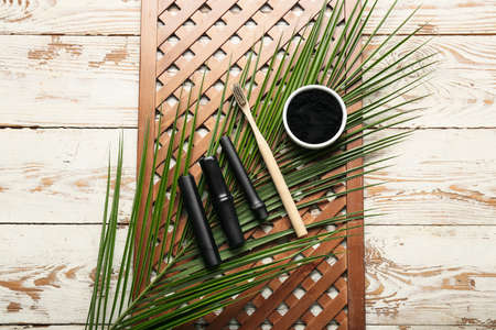 Composition with activated charcoal tooth powder, bamboo sticks and brush on white wooden backgroundの写真素材