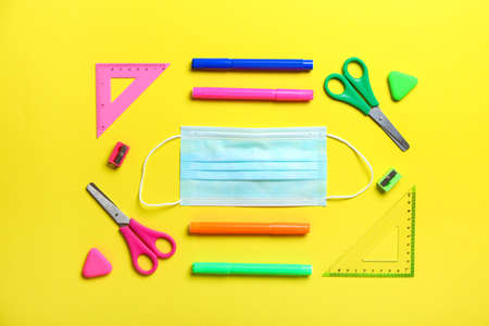 Stationery supplies with medical mask on color background