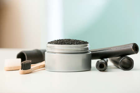 Jar with activated charcoal tooth powder, brushes and bamboo sticks on tableの写真素材