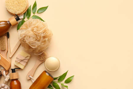 Set of bath supplies with loofah and plant branches on beige background