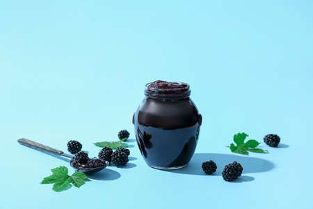 Jar of tasty blackberry jam and berries on color backgroundの写真素材
