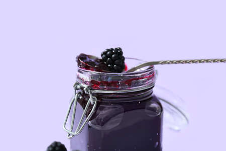 Jar of tasty blackberry jam on color background, closeup