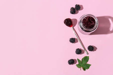 Jar and spoon with tasty blackberry jam on color backgroundの写真素材