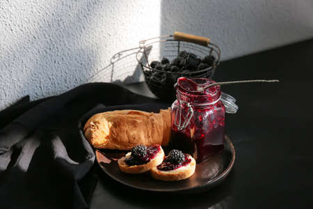 Composition with jar of tasty blackberry jam and sandwiches on tableの写真素材