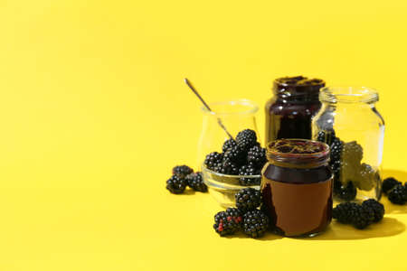 Composition with jars of tasty blackberry jam and berries on color backgroundの写真素材