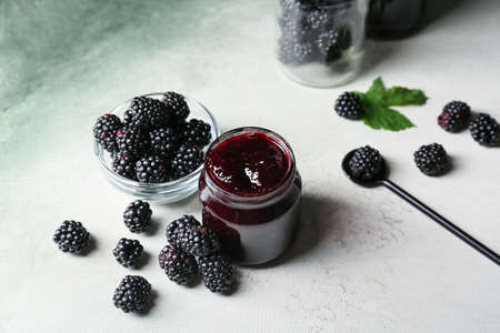 Composition with jar of tasty blackberry jam and berries on light backgroundの写真素材