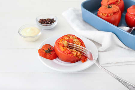 Plate with tasty stuffed tomato on light backgroundの写真素材