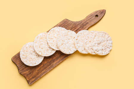 Board with puffed rice crackers on color backgroundの写真素材