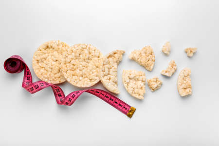 Rice crackers and measuring tape on white backgroundの写真素材