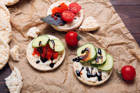 Composition with crispy rice crackers, red caviar and vegetables on wooden backgroundの写真素材