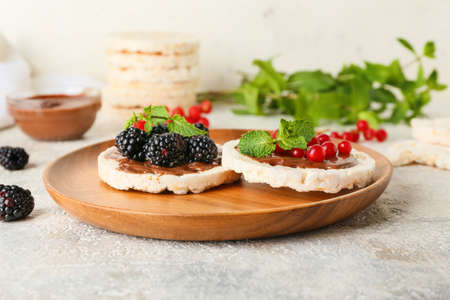 Plate with puffed rice crackers and berries on light background, closeup