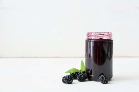 Jar of tasty blackberry jam on light backgroundの写真素材