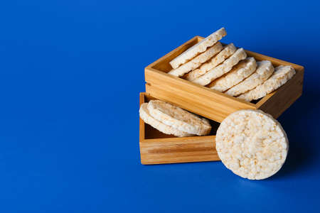 Wooden boxes with crispy rice crackers on color background