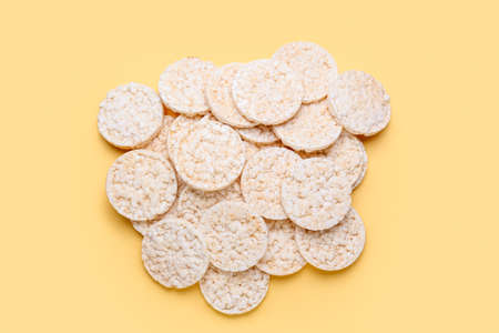 Pile of crispy rice crackers on color background