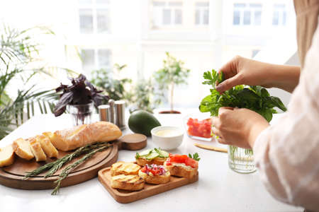 Woman cooking tasty vegetarian bruschettas at table in kitchenの写真素材