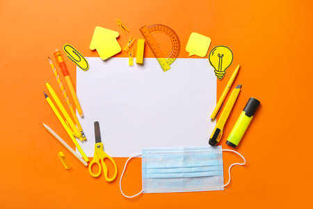 Blank paper sheet, set of stationery and medical mask on color background