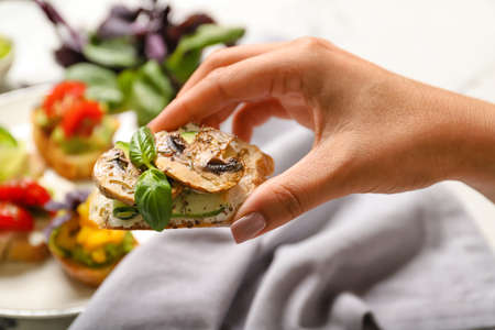 Female hand with delicious vegetarian bruschetta, closeup