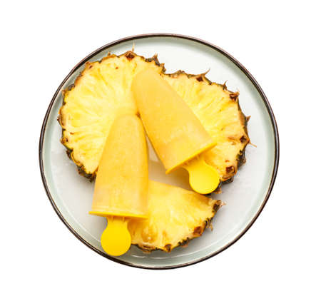 Plate with tasty pineapple popsicles on white backgroundの写真素材