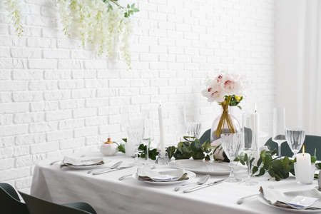 Beautiful table setting for wedding celebration with burning candles in restaurant