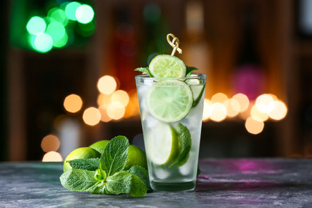 Glass of cold mojito on table against blurred lightsの写真素材