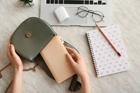 Female hands with medical mask case, laptop, earphones and eyeglasses on light background