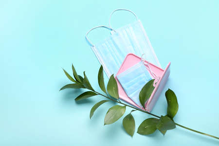 Medical masks with case and green branch on color background