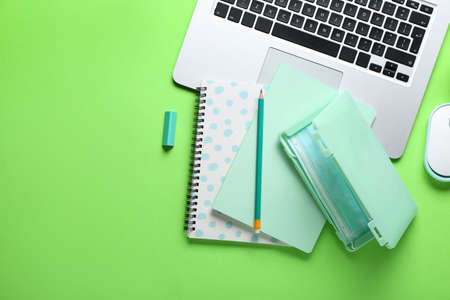 Medical mask with case, laptop and notebooks on green background
