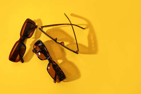 Stylish female sunglasses on color background
