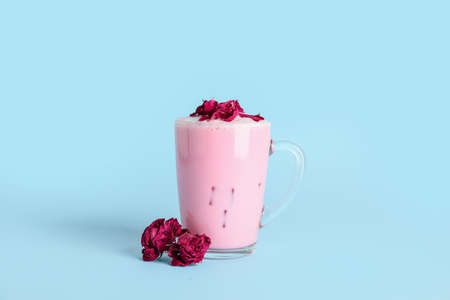 Cup of tasty rose latte on color background