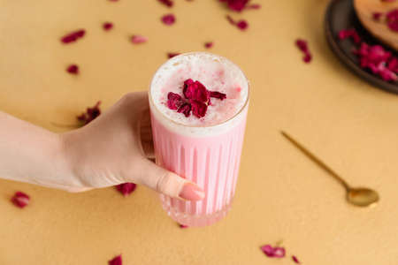 Female hand with glass of tasty rose latte