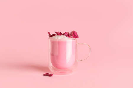 Cup of tasty rose latte on color background