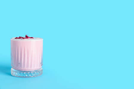 Glass of tasty rose latte on color background