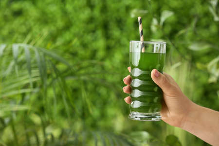 Female hand with glass of juice healthy outdoors, closeupの写真素材