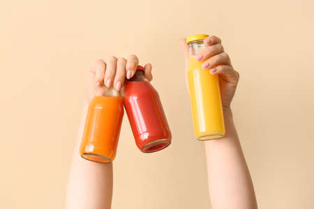 Female hands with glass of healthy juice on color backgroundの写真素材