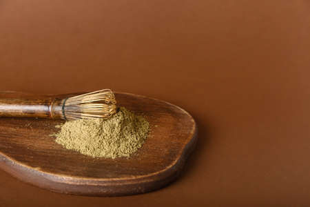 Wooden board with hojicha powder and chasen on brown backgroundの写真素材